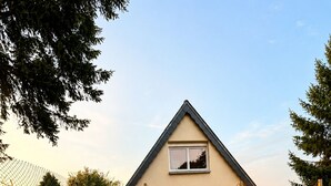 Ein Haus mit überdachter Terrasse, Rasen und Lichterketten.