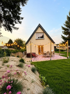 Une maison dotée d’un patio couvert, d’une pelouse et de guirlandes lumineuses.