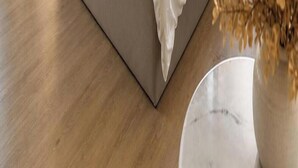 Ein Holzboden mit einer weißen Vase und einem marmorähnlichen Gegenstand.