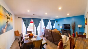 A modern living room with a sofa, dining table, and a TV. - Azure Haven - Red Rock Views . Walkable Trails & Eats (Sedona)
