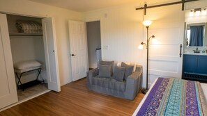 A room with a bed, a bedside table, a chair, a wardrobe, and a door leading to another room. - Azure Haven - Red Rock Views . Walkable Trails & Eats (Sedona)