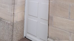 Eine weiße Tür mit kleinem Fenster und Klingel.