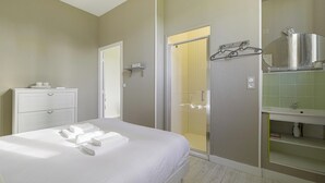 Ein Hotelzimmer mit Bett, Badezimmer mit Spiegel und Waschbecken sowie einer Duschkabine.