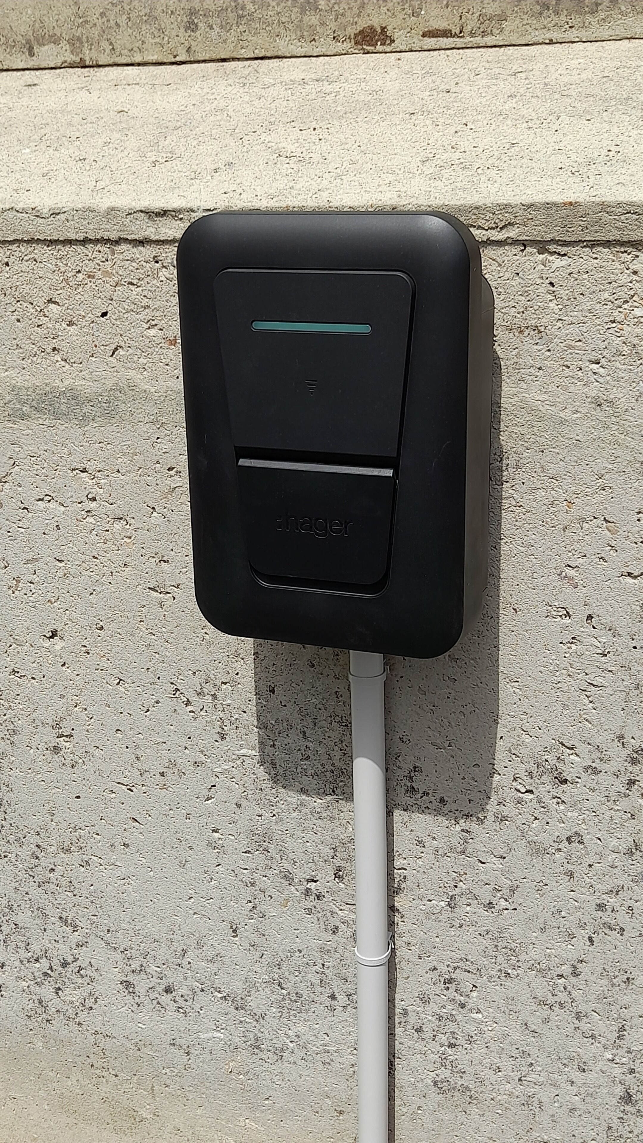 Une boîte électrique noire pour l’extérieur, munie d’un poteau blanc fixé à celle-ci, et montée sur une surface en béton.