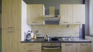 Eine moderne Küche mit Holzschränken, einem Gasherd, einer Kaffeemaschine und einem Spülbecken.