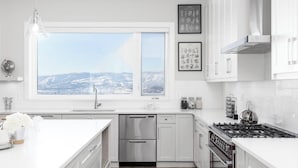 Eine moderne Küche mit einem großen Fenster, Edelstahlgeräten und weißen Schränken.