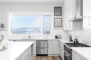 Eine moderne Küche mit einem großen Fenster, Edelstahlgeräten und weißen Schränken.