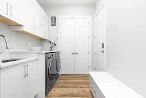 Eine kleine Küche mit Waschmaschine, Spüle und Holzboden.