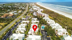Vista aérea de una zona residencial costera con playa, carreteras y una ubicación señalada.