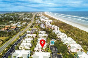Luftaufnahme einer Küstenwohngegend mit Strand, Straßen und einem markierten Punkt.