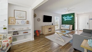 Una sala de estar con un sofá, una mesa de centro y un televisor montado en la pared.