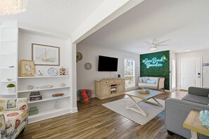 Ein Wohnzimmer mit einer Couch, einem Couchtisch und einem an der Wand befestigten Fernseher.