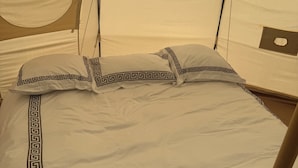 Uma cama com padrão geométrico em branco e preto, uma janela circular e uma estrutura semelhante a uma tenda.