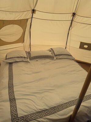 Ein Bett mit einem schwarz-weißen geometrischen Muster, einem runden Fenster und einer zeltartigen Konstruktion.