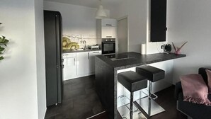 A modern kitchen with a central island, bar stools, and a refrigerator. - FarawayHomes Studio Bruck 17 (Bruck an der Mur)