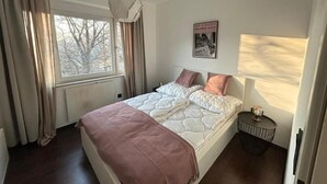A bedroom with a bed, a window, a wall clock, and a poster. - FarawayHomes Studio Bruck 17 (Bruck an der Mur)
