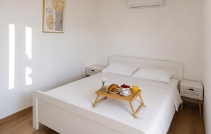 Ein ordentlich bezogenes Bett mit einem Frühstücksbrett, weißer Bettwäsche und einem schlichten Nachttisch.
