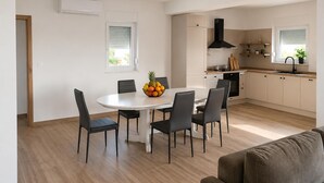 Une cuisine moderne avec un coin repas, comprenant une table ronde, des chaises et un panier de fruits.