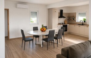 Eine moderne Küche mit Essbereich, ausgestattet mit einem runden Tisch, Stühlen und einer Obstschale.