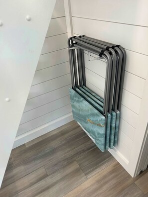 Un coin de pièce avec un mur blanc, un plancher en bois et un étagère en métal sur laquelle est suspendu un objet bleu à motifs.