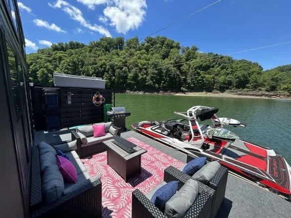 Interior de barco con sofá, cojines y una parrilla.