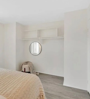 A bedroom with a bed, a round mirror, and built-in shelving.