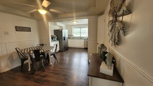 A kitchen with a dining area, a ceiling fan, and a sign that reads 'FARMHOUSE.' - Kansas City 3-bedroom farmhouse on peaceful acreage near Legends entertainment! (Kansas City)
