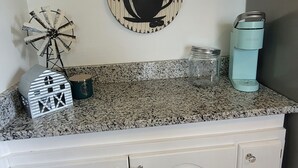 A kitchen with a coffee-themed wall decoration, a windmill, a jar, and a Keurig coffee maker. - Kansas City 3-bedroom farmhouse on peaceful acreage near Legends entertainment! (Kansas City)