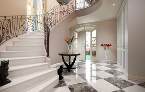 A grand staircase with ornate metal railings, a checkered marble floor, and a view into a bright room with a door leading outside. - Luxurious home in Vabriga (Vabriga)