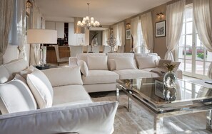 A modern living room with a sectional sofa, a glass coffee table, and a chandelier. - Luxurious home in Vabriga (Vabriga)