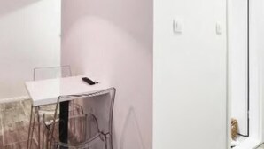 Una stanza con un tavolo bianco, sedie trasparenti e una porta che dà su un altro ambiente.