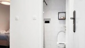 Un bagno con il water, una zona doccia e una porta con maniglia.