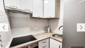 Una cucina moderna con mobili bianchi, piano cottura nero e lavandino in acciaio inossidabile.