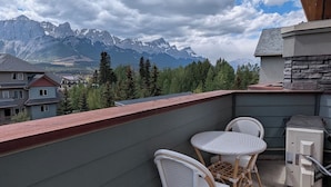 A balcony with wicker chairs, a small table, and a heater. - Three Peaks Penthouse [3 Hot Tubs & Pool] (Canmore)