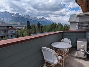 Ein Balkon mit Korbstühlen, einem kleinen Tisch und einem Heizgerät.