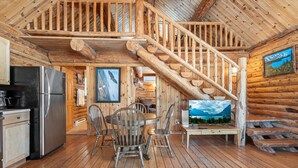 Interno di una baita in legno con cucina, sala da pranzo e una scala.