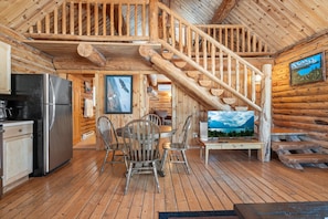 Ein Holzblock-Innenraum mit Küche, Essbereich und einer Treppe.