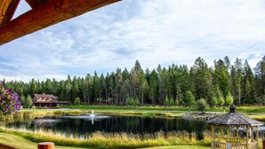 Un gazebo vicino a uno stagno, con una casa sullo sfondo.