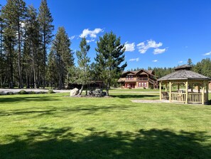 Eine Lodge mit einem großen Holzbau, einem gepflegten Rasen und hohen Kiefern im Hintergrund.