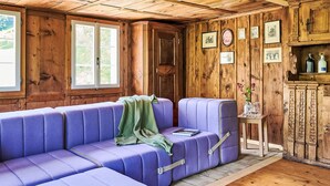 Ein Zimmer mit Holzboden, einem violetten Sofa, einer Tür und gerahmten Bildern an der Wand.