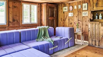 Une pièce avec un plafond en bois, un canapé violet, une porte et des tableaux encadrés accrochés au mur.