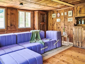 Ein Zimmer mit Holzboden, einem violetten Sofa, einer Tür und gerahmten Bildern an der Wand.