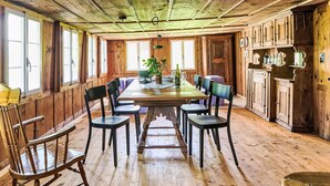 Ein Esszimmer aus Holz mit einem langen Tisch, Stühlen und einem Blumentopf.