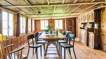 Une salle à manger en bois avec une longue table, des chaises et une plante en pot.