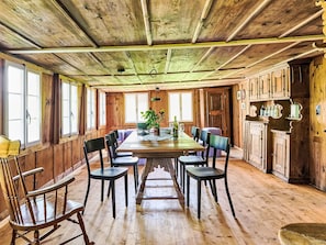 Ein Esszimmer aus Holz mit einem langen Tisch, Stühlen und einem Blumentopf.