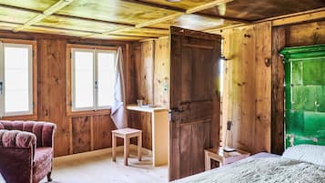 Une pièce de cabane en bois comprenant un lit, une chaise, un bureau et un placard vert.