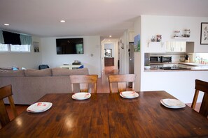 Un comedor con una mesa y sillas de madera, un sofá y una cocina al fondo.