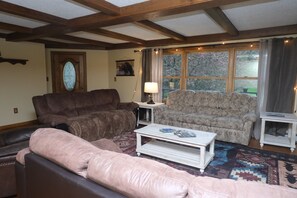 A living room with a brown sofa, a patterned armchair, and a white coffee table.
