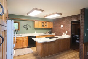 A kitchen with wooden cabinets, a marble countertop, and a brick accent wall.