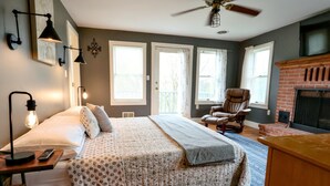A bedroom with a bed, a chair, a fireplace, and a ceiling fan. - The Homestead at Anderson Ridge |Pool & Trails (Schellsburg)